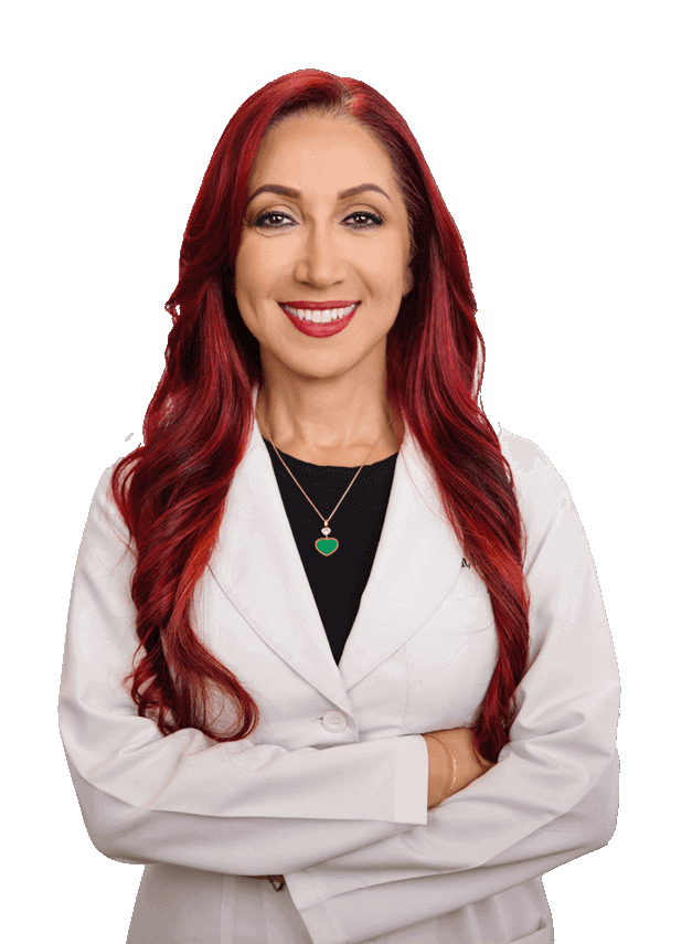 A person with long, red hair and a friendly smile is wearing a white lab coat over a black top, with arms crossed.